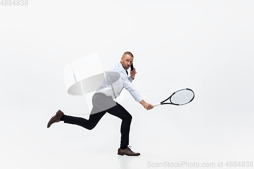 Image of Time for movement. Man in office clothes plays tennis isolated on white studio background.