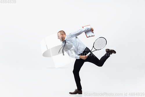 Image of Time for movement. Man in office clothes plays tennis isolated on white studio background.