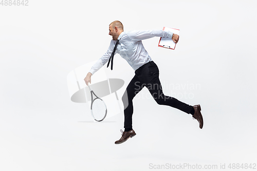 Image of Time for movement. Man in office clothes plays tennis isolated on white studio background.