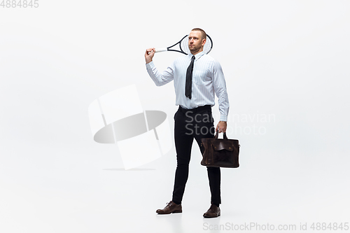 Image of Time for movement. Man in office clothes plays tennis isolated on white studio background.