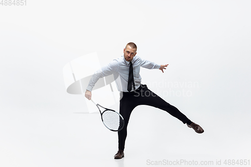 Image of Time for movement. Man in office clothes plays tennis isolated on white studio background.