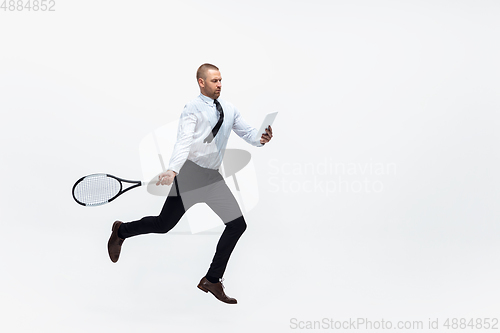 Image of Time for movement. Man in office clothes plays tennis isolated on white studio background.