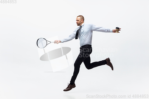 Image of Time for movement. Man in office clothes plays tennis isolated on white studio background.