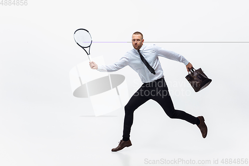 Image of Time for movement. Man in office clothes plays tennis isolated on white studio background.