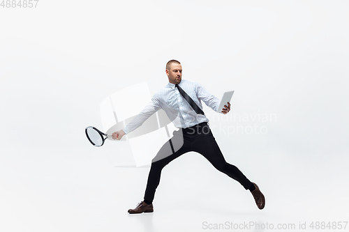 Image of Time for movement. Man in office clothes plays tennis isolated on white studio background.