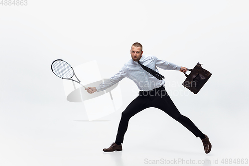 Image of Time for movement. Man in office clothes plays tennis isolated on white studio background.