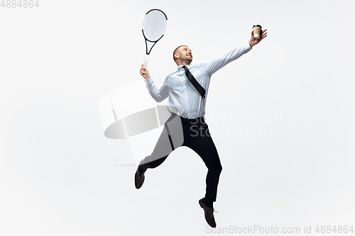 Image of Time for movement. Man in office clothes plays tennis isolated on white studio background.