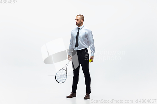 Image of Time for movement. Man in office clothes plays tennis isolated on white studio background.