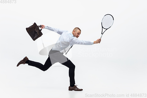 Image of Time for movement. Man in office clothes plays tennis isolated on white studio background.