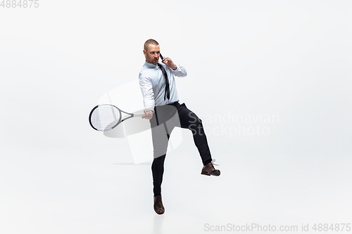 Image of Time for movement. Man in office clothes plays tennis isolated on white studio background.