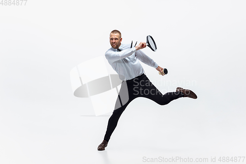 Image of Time for movement. Man in office clothes plays tennis isolated on white studio background.