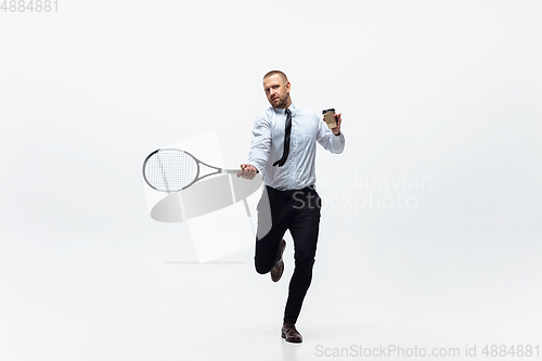 Image of Time for movement. Man in office clothes plays tennis isolated on white studio background.