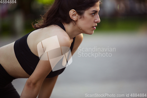 Image of Young female athlete training in the city street in summer sunshine. Beautiful woman practicing, working out. Concept of sport, healthy lifestyle, movement, activity.