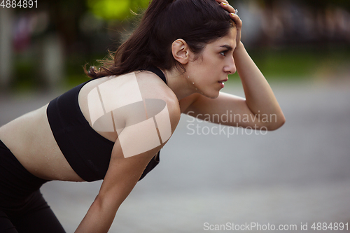 Image of Young female athlete training in the city street in summer sunshine. Beautiful woman practicing, working out. Concept of sport, healthy lifestyle, movement, activity.