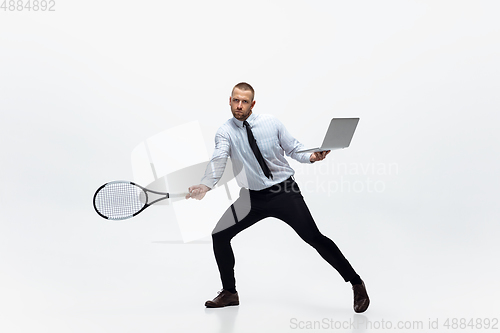 Image of Time for movement. Man in office clothes plays tennis isolated on white studio background.