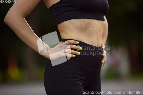 Image of Young female athlete training in the city street in summer sunshine. Beautiful woman practicing, working out. Concept of sport, healthy lifestyle, movement, activity.