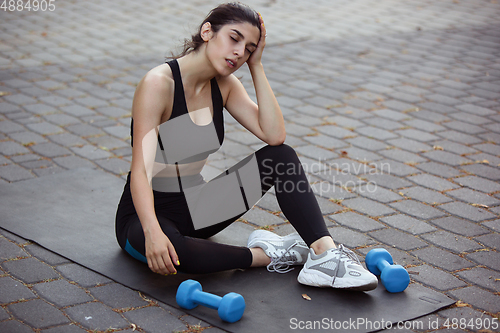 Image of Young female athlete training in the city street in summer sunshine. Beautiful woman practicing, working out. Concept of sport, healthy lifestyle, movement, activity.