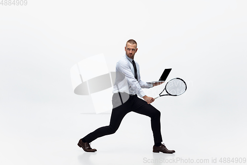 Image of Time for movement. Man in office clothes plays tennis isolated on white studio background.