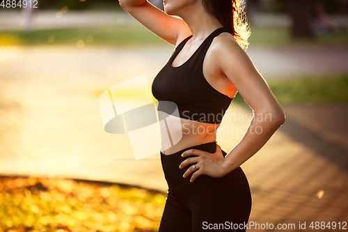 Image of Young female athlete training in the city street in summer sunshine. Beautiful woman practicing, working out. Concept of sport, healthy lifestyle, movement, activity.