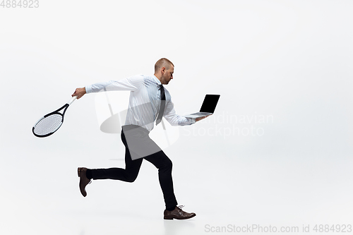 Image of Time for movement. Man in office clothes plays tennis isolated on white studio background.