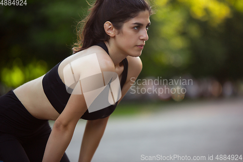 Image of Young female athlete training in the city street in summer sunshine. Beautiful woman practicing, working out. Concept of sport, healthy lifestyle, movement, activity.