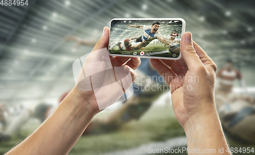 Image of Close up hands holding smartphone viewing sport, online translation, streaming of championship