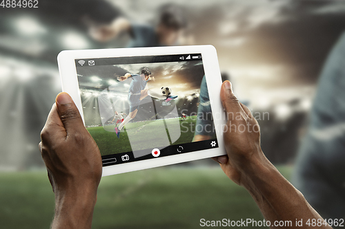 Image of Close up hands holding tablet viewing sport, online translation, streaming of championship