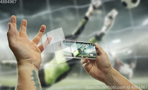 Image of Close up hands holding smartphone viewing sport, online translation, streaming of championship