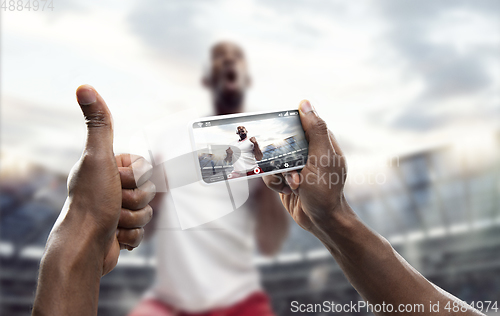 Image of Close up hands holding smartphone viewing sport, online translation, streaming of championship