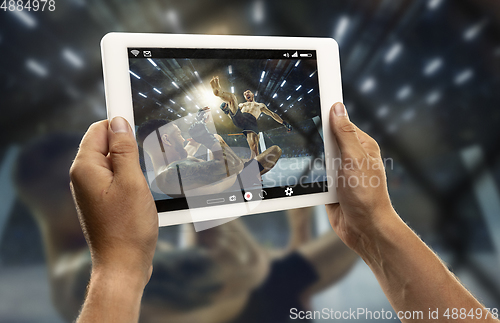 Image of Close up hands holding tablet viewing sport, online translation, streaming of championship