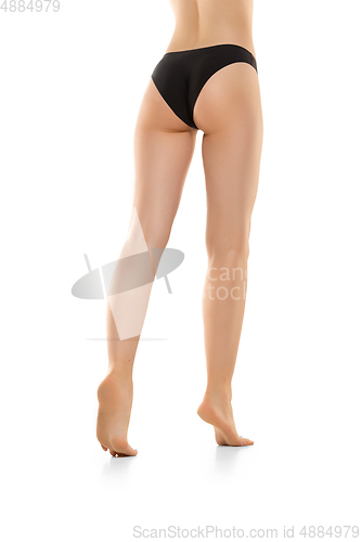 Image of Beautiful female legs, buttlocks and belly isolated on white background. Sportive, sensual body with well-kept skin in underwear.