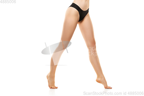 Image of Beautiful female legs, buttlocks and belly isolated on white background. Sportive, sensual body with well-kept skin in underwear.