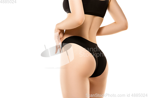 Image of Beautiful female legs, buttlocks and belly isolated on white background. Sportive, sensual body with well-kept skin in underwear.