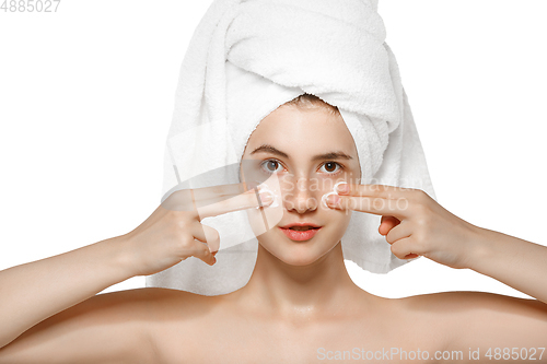 Image of Beauty Day. Woman wearing towel doing her daily skincare routine isolated on white studio background