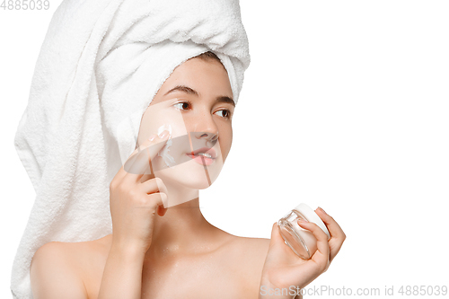 Image of Beauty Day. Woman wearing towel doing her daily skincare routine isolated on white studio background