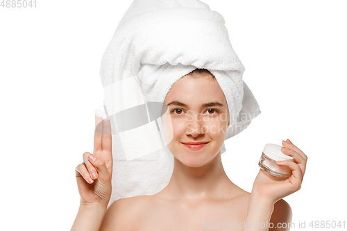 Image of Beauty Day. Woman wearing towel doing her daily skincare routine isolated on white studio background