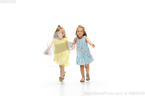 Image of Happy little caucasian girls jumping and running isolated on white background