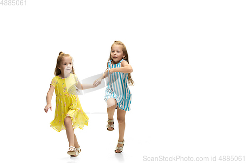 Image of Happy little caucasian girls jumping and running isolated on white background