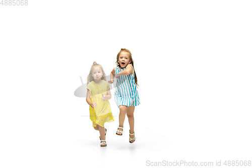 Image of Happy little caucasian girls jumping and running isolated on white background