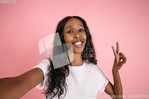 Image of Cheerful african-american young woman isolated on pink background, emotional and expressive