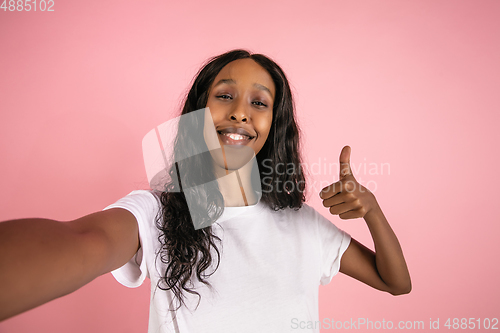 Image of Cheerful african-american young woman isolated on pink background, emotional and expressive