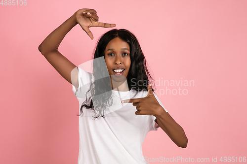 Image of Cheerful african-american young woman isolated on pink background, emotional and expressive