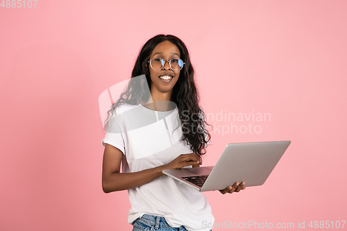 Image of Cheerful african-american young woman isolated on pink background, emotional and expressive