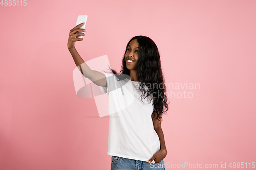 Image of Cheerful african-american young woman isolated on pink background, emotional and expressive