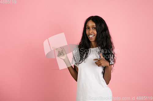 Image of Cheerful african-american young woman isolated on pink background, emotional and expressive