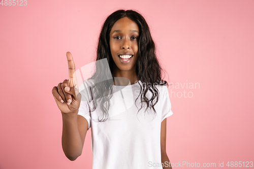 Image of Cheerful african-american young woman isolated on pink background, emotional and expressive