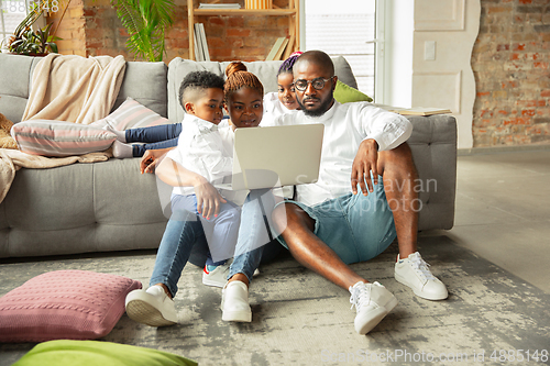 Image of Young african family during quarantine, insulation spending time together at home