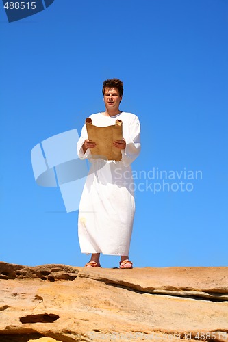 Image of man reading scroll in rocky desert land scape