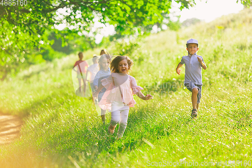 Image of Kids, children running on meadow in summer\'s sunlight