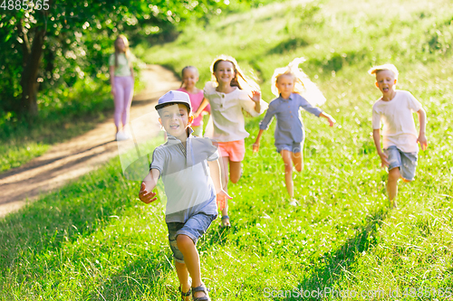 Image of Kids, children running on meadow in summer\'s sunlight
